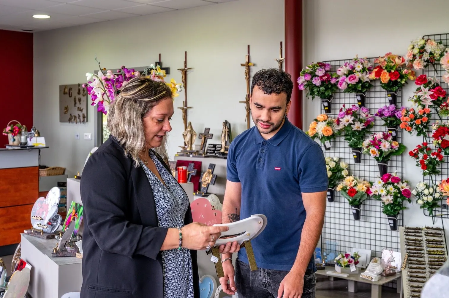 Conseillère funéraire accompagnant un client dans le choix d'articles d'hommage en magasin